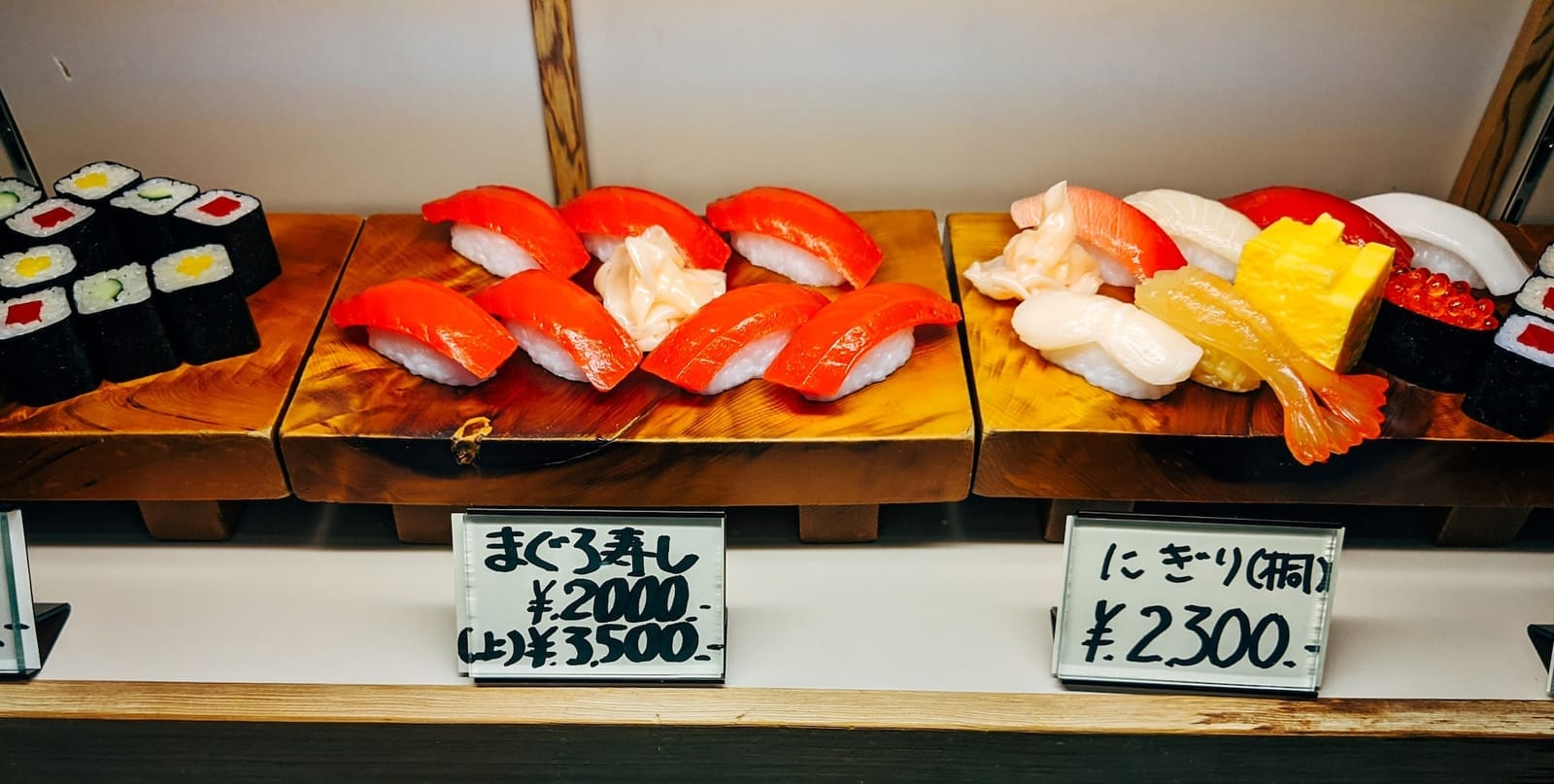 Assorted sushi nigiri and sashimi sushi on a wooden shelf.