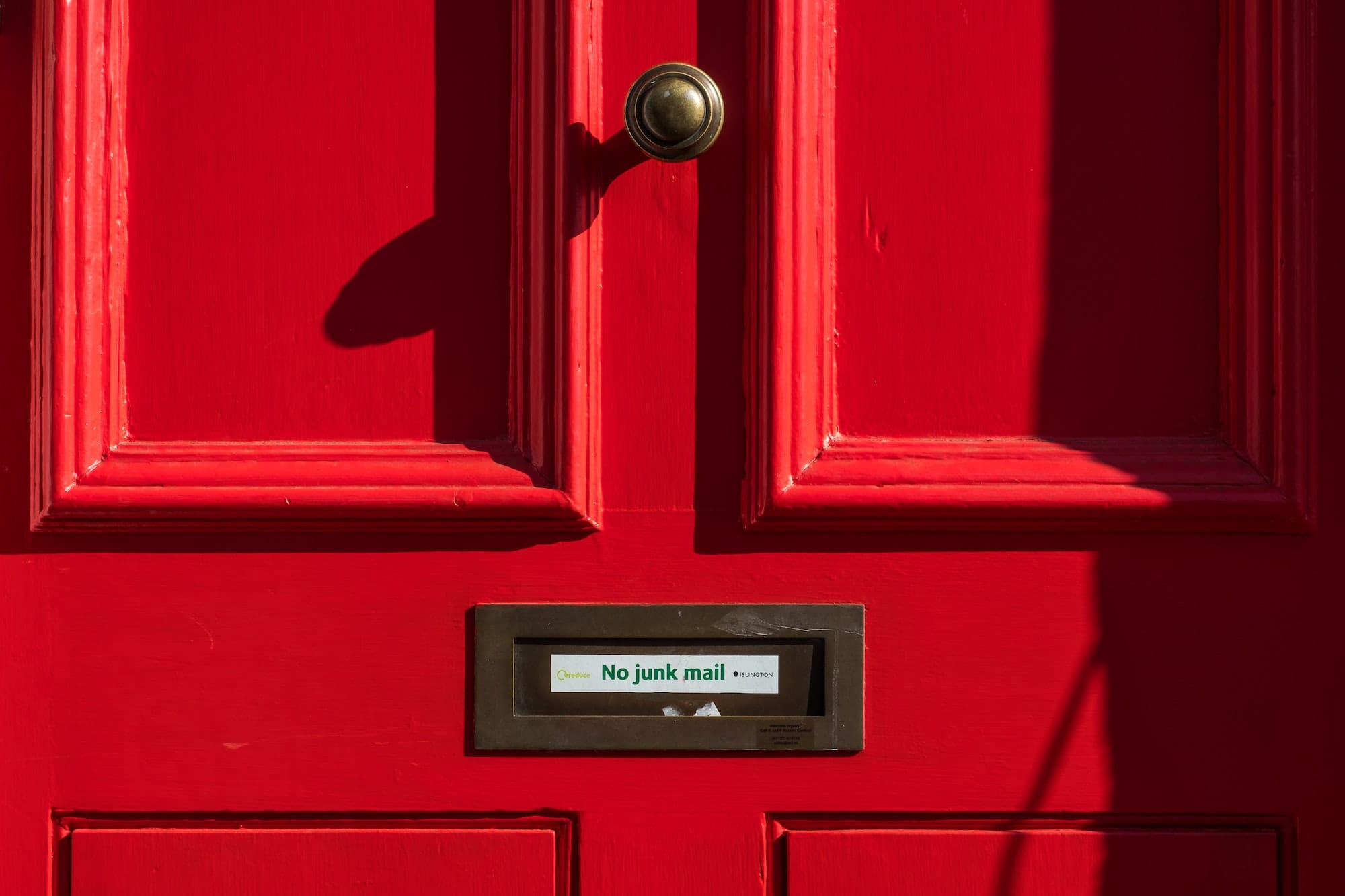 closed red wooden door with a comment asking for no junk mail or spam