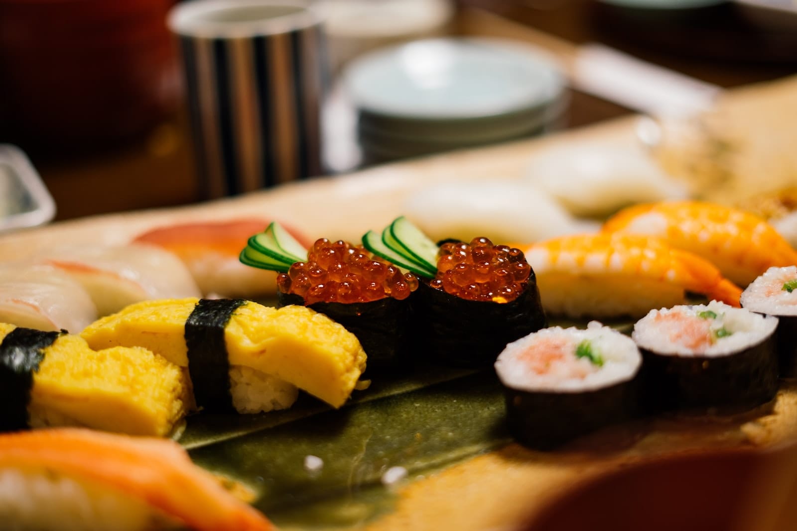 Cooked sushi on a plate next to egg nigiri.