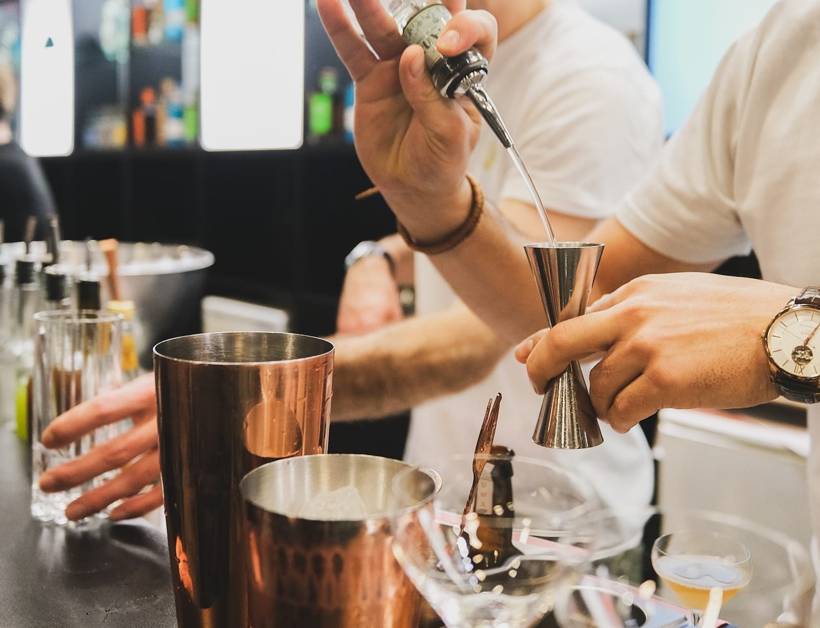 Bartender pouring alcohol into a jigger for a cocktail.