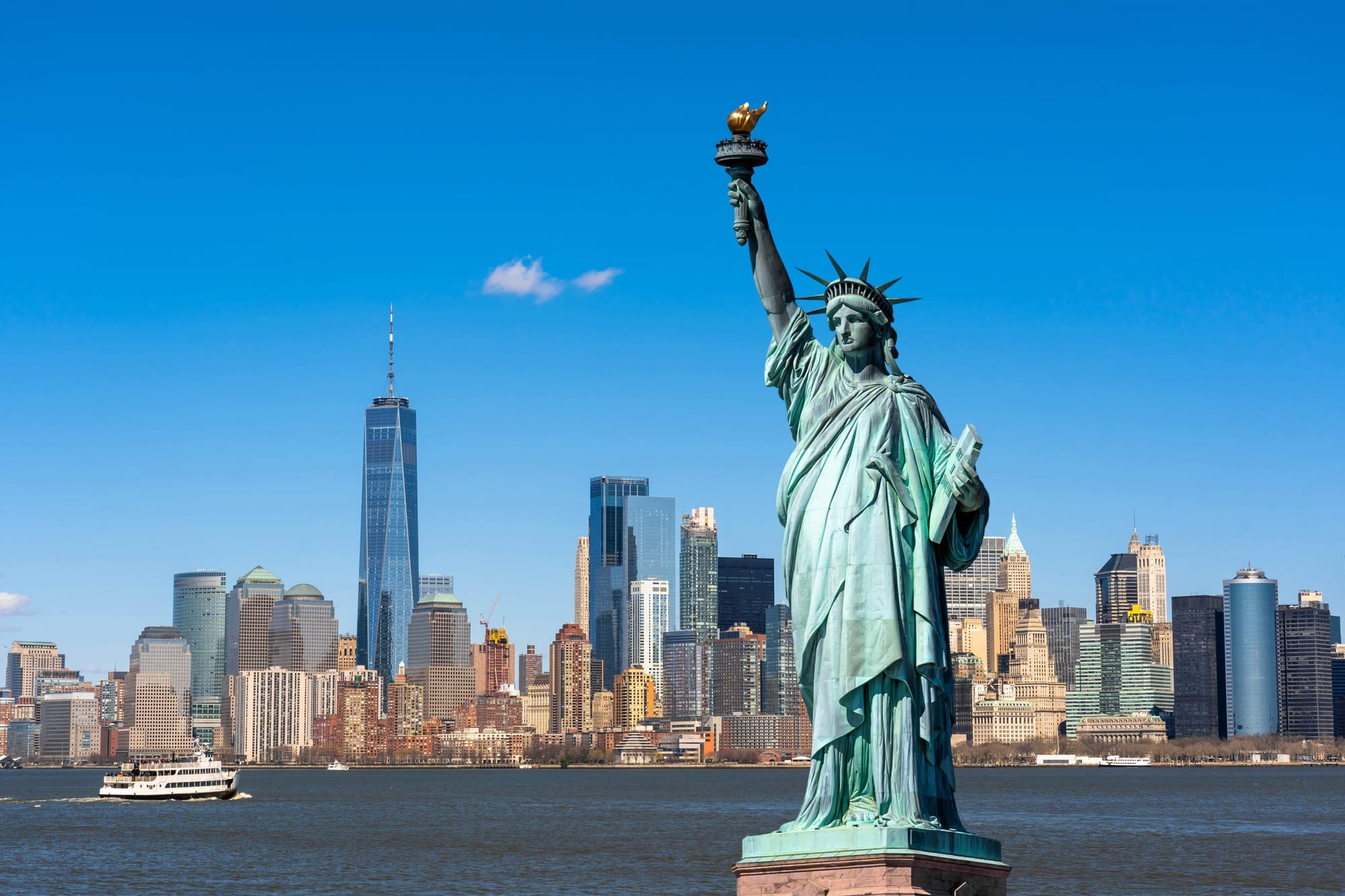 Statue of liberty in front of the New York skyscape.