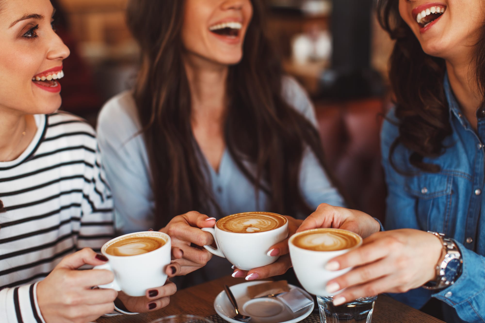 Guests in a cafe coffee shop bistro smiling and drinking coffee and lattes.