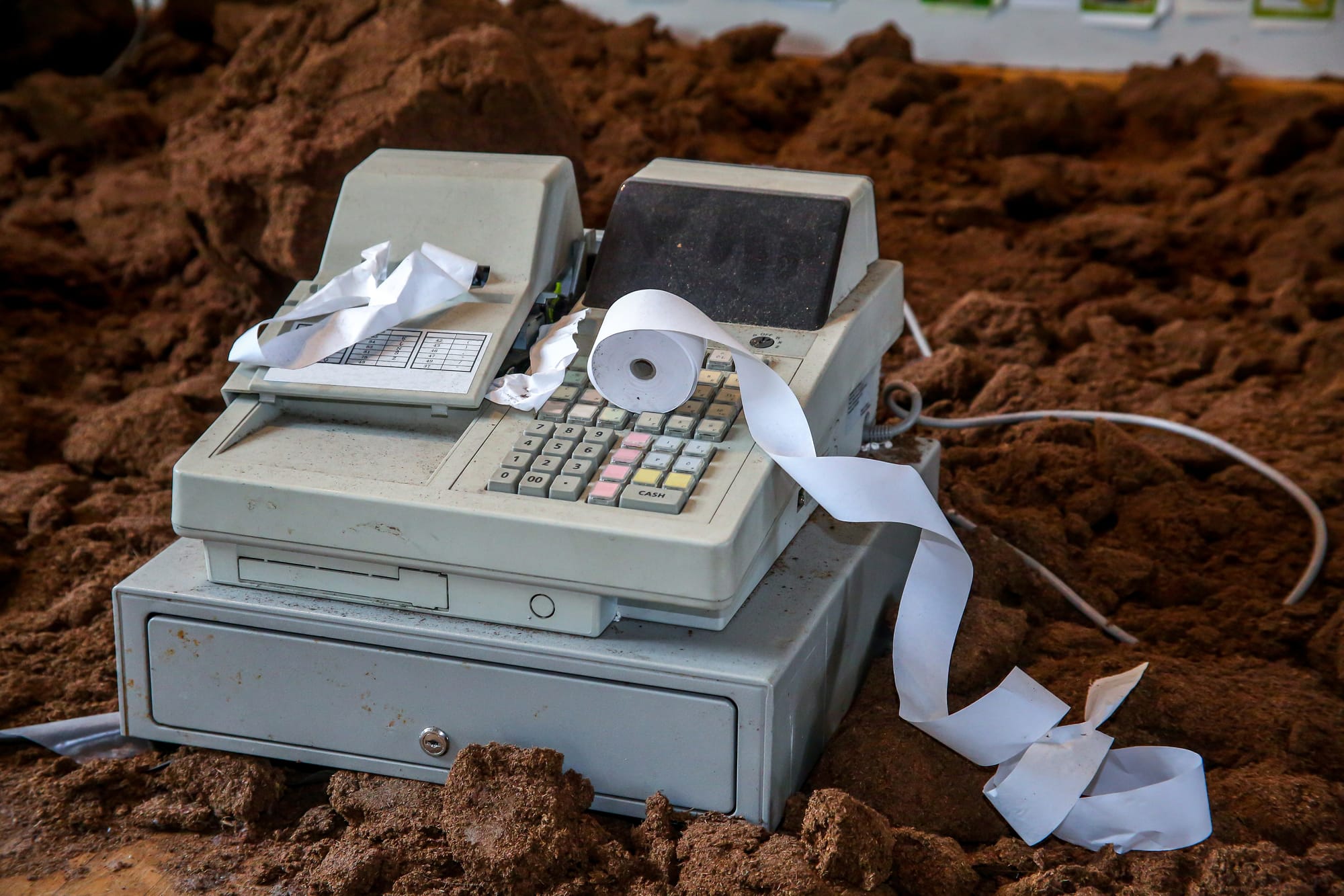 Legacy POS cash register with cash drawers with jammed paper receipts in dirt