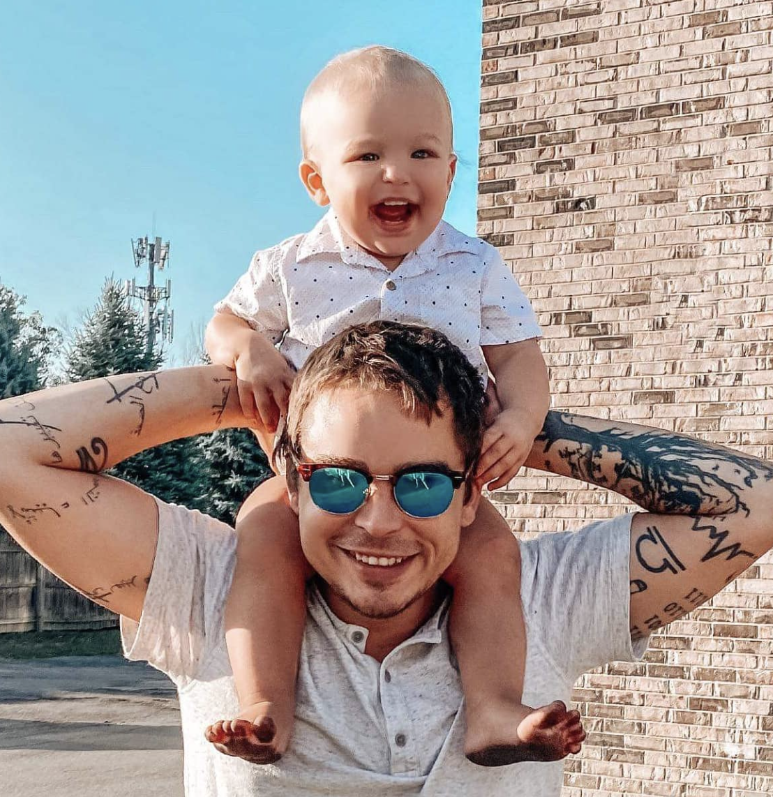 Fine dining chef posing with his smiling son outside a restaurant