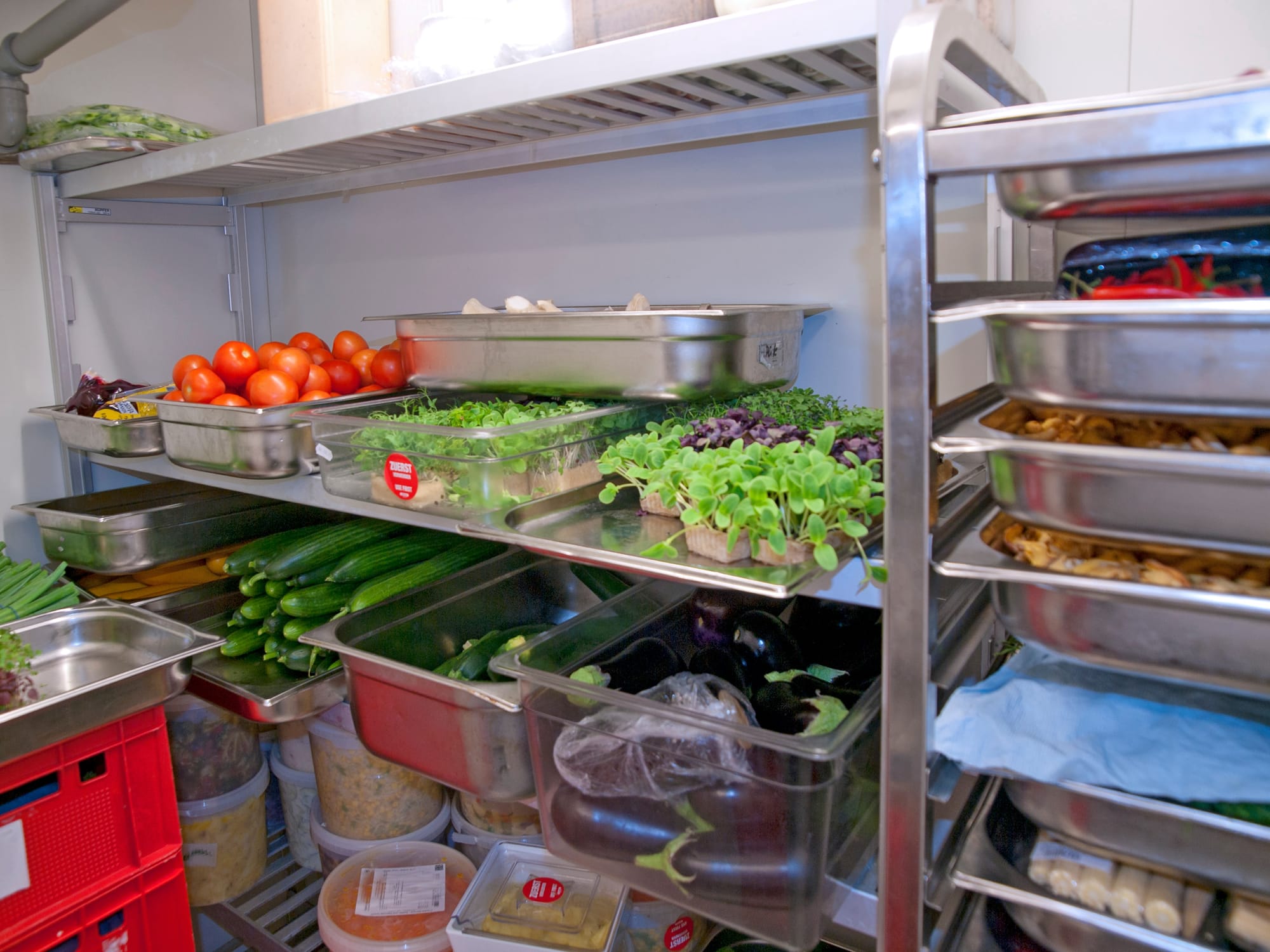Restaurant shelving with containers of produce, sauces, and prepped entrees