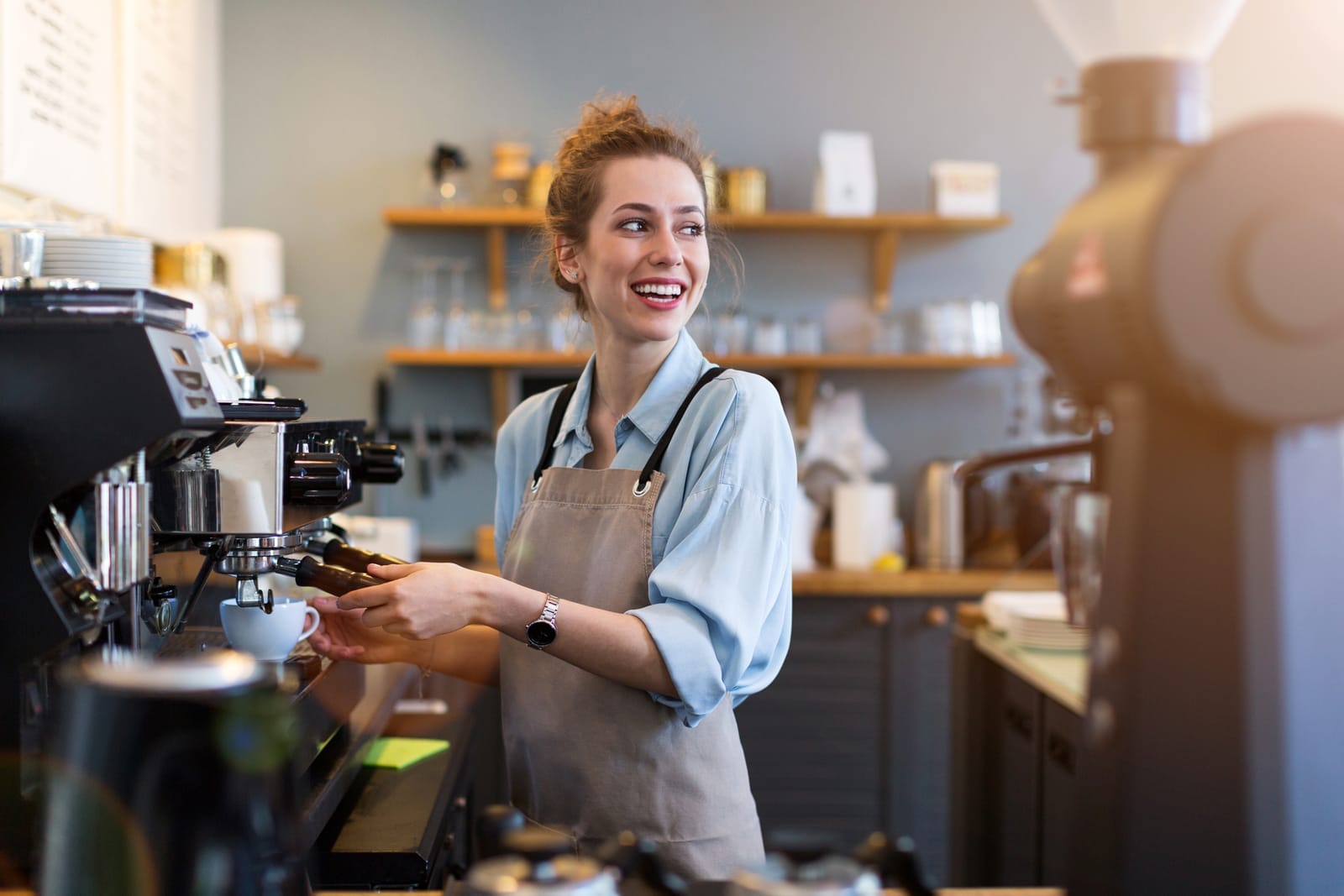 Barista smiling and brewing coffee espresso for guests in the morning.