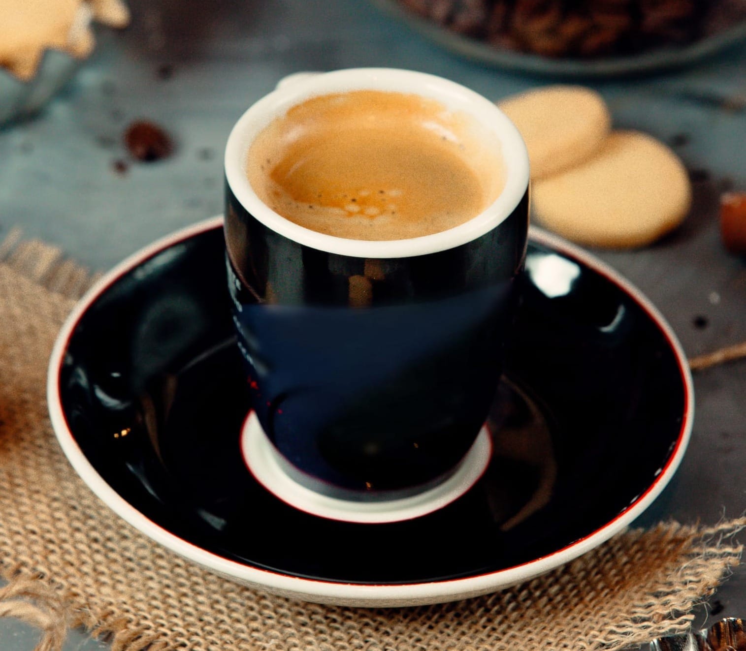 Cup of Americano coffee with coffee shop ingredients surrounding it.