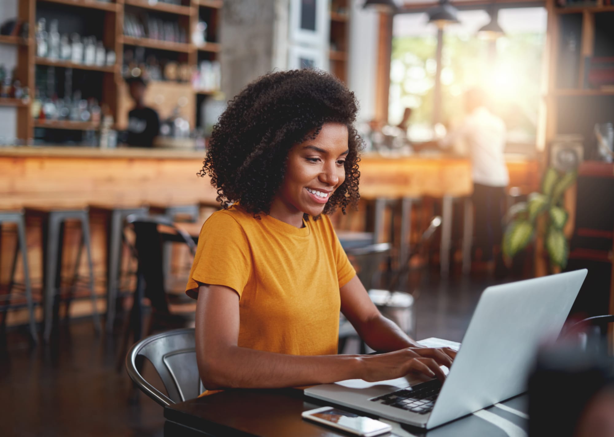 Woman in restaurant typing and Google searching best restaurant menus.