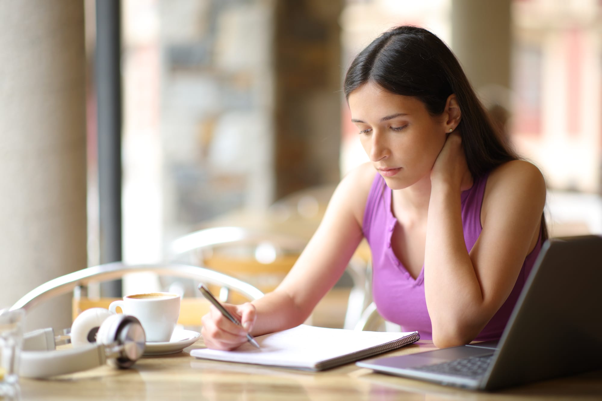 Woman in coffee shop drafting up name ideas for her own coffee cafe business.