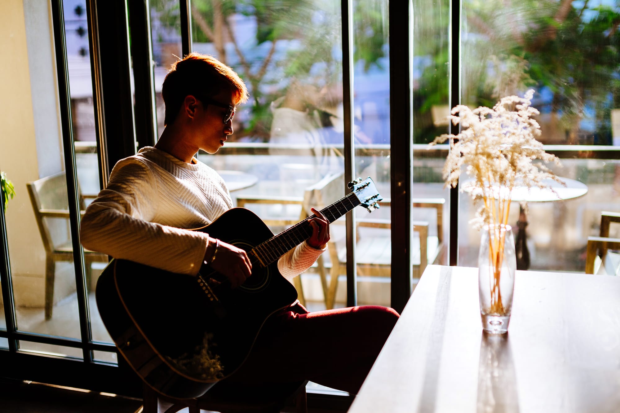 Guitar player in coffee shop bistro cafe next to a seating arrangement.