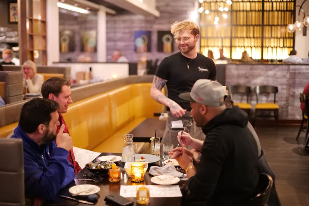 Server engages with guests at a restaurant.