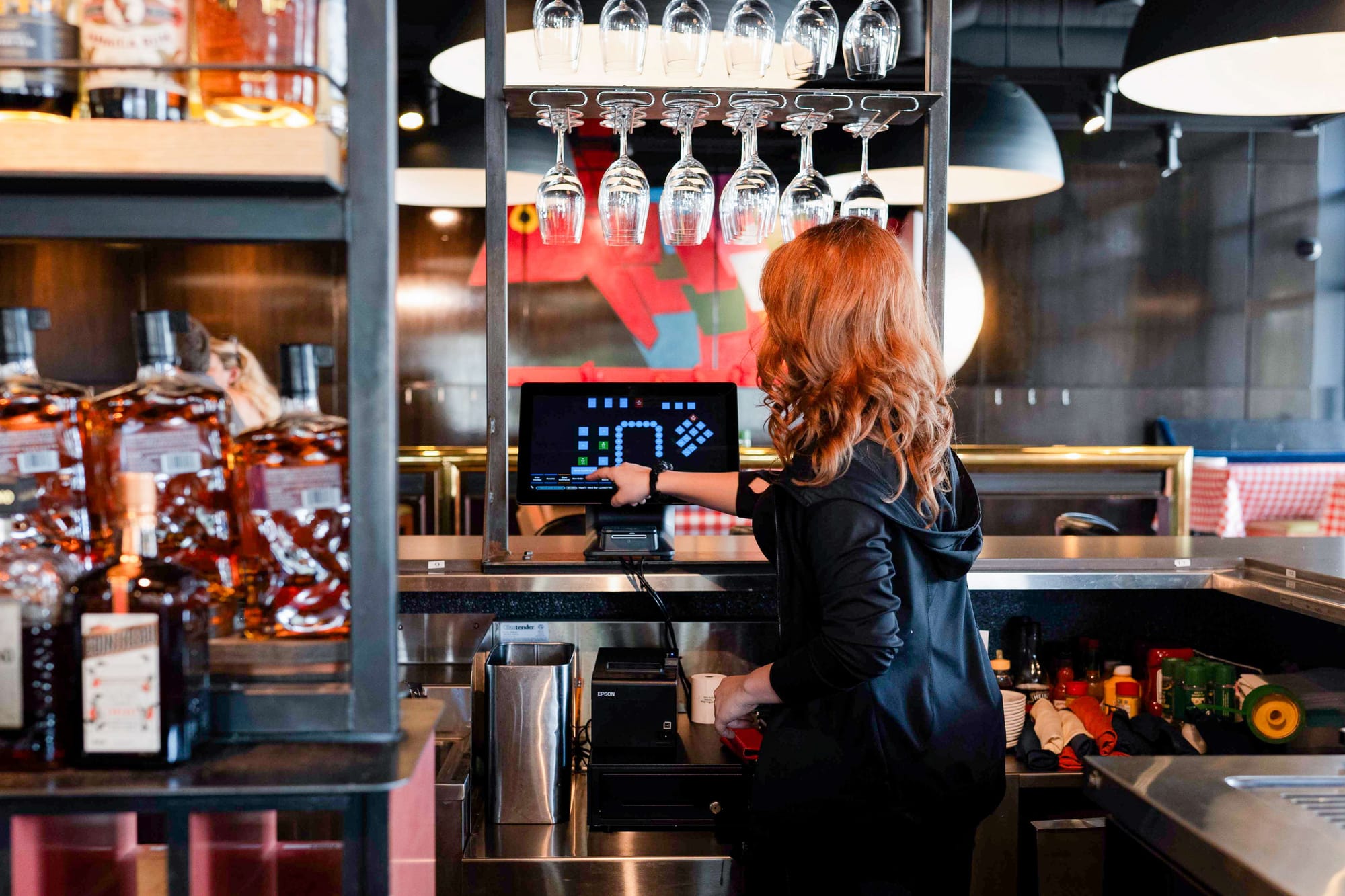 A bartender taps in an order on a POS screen