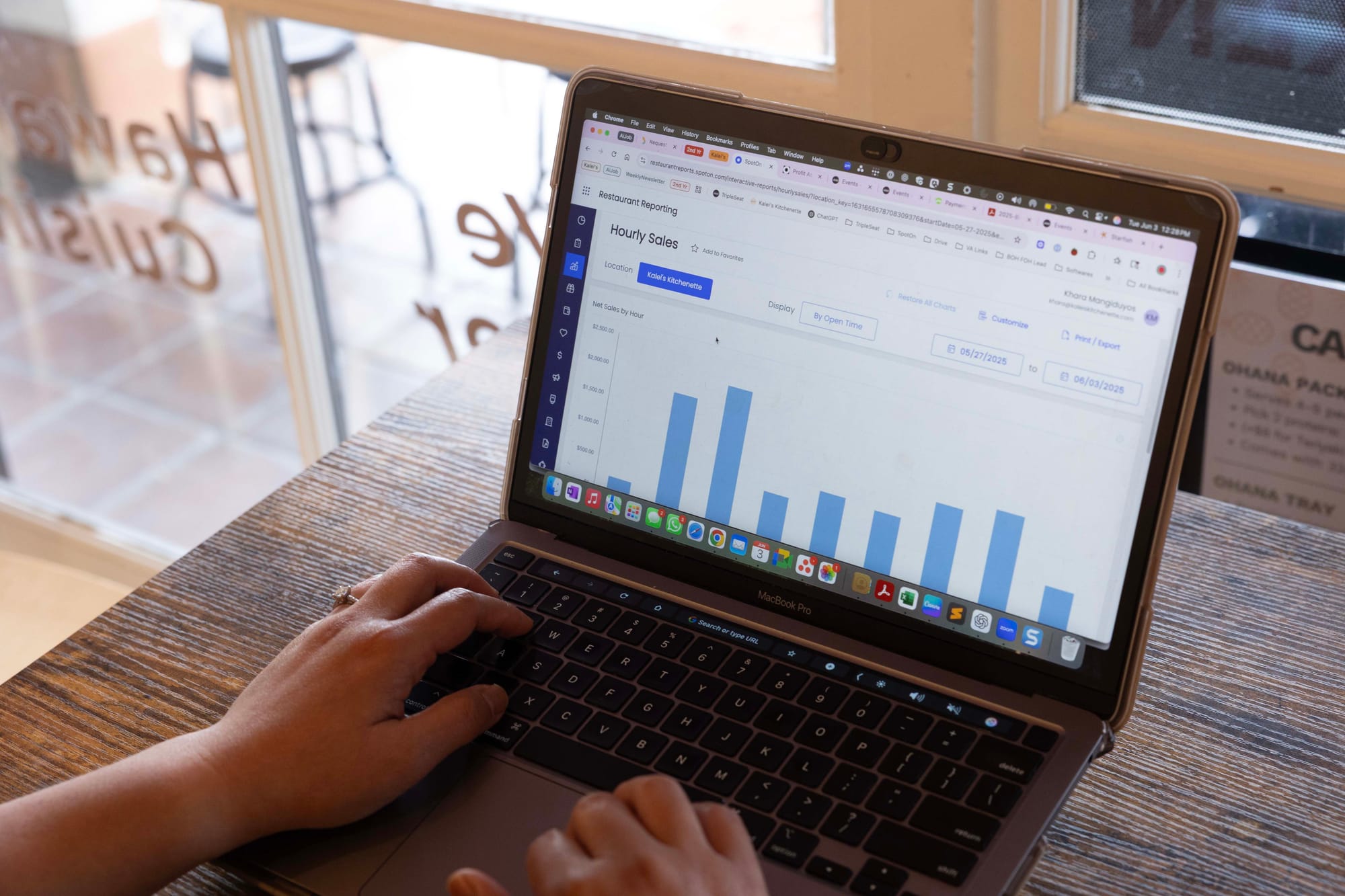 A restaurant owner checks their POS sales reports on a laptop