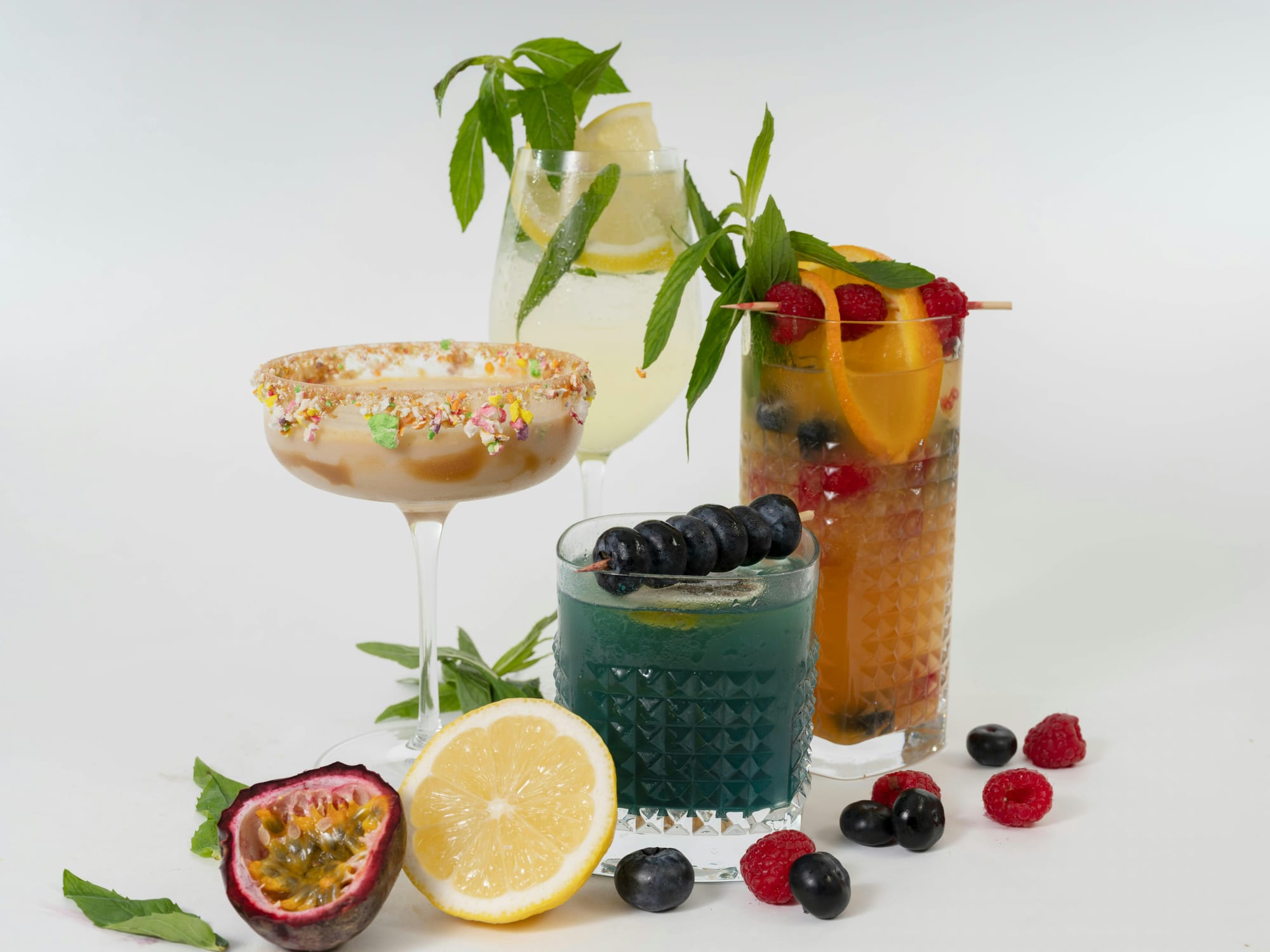 Four non-alcoholic drinks with different fruits and herbs.