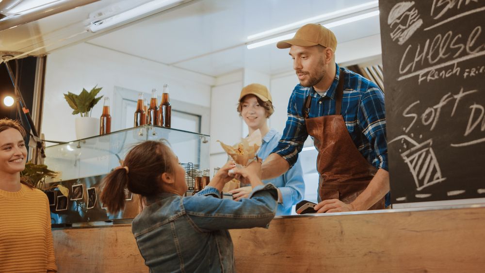 Woman getting food from an employee inside a food truck.