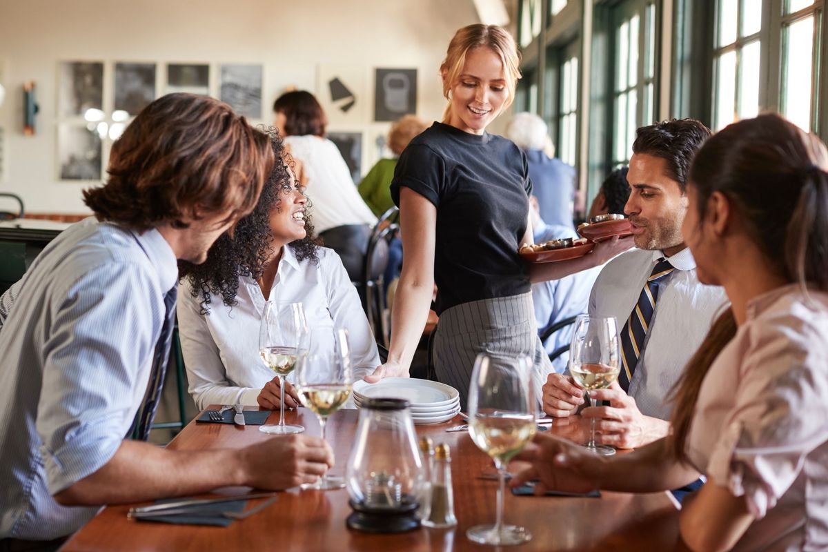 A server delivers dishes to a table of hungry guests