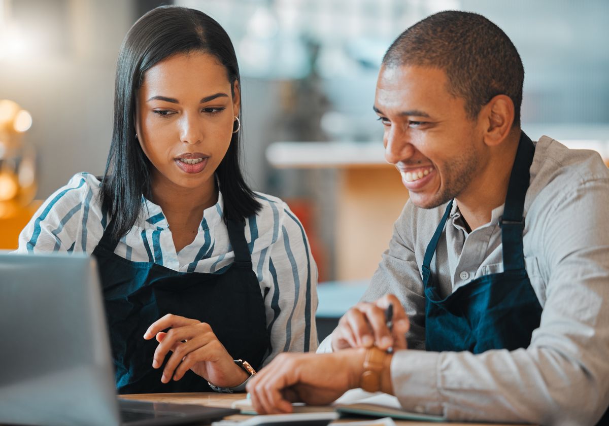 2 restaurant managers review guest surveys on a laptop to measure guest satisfaction