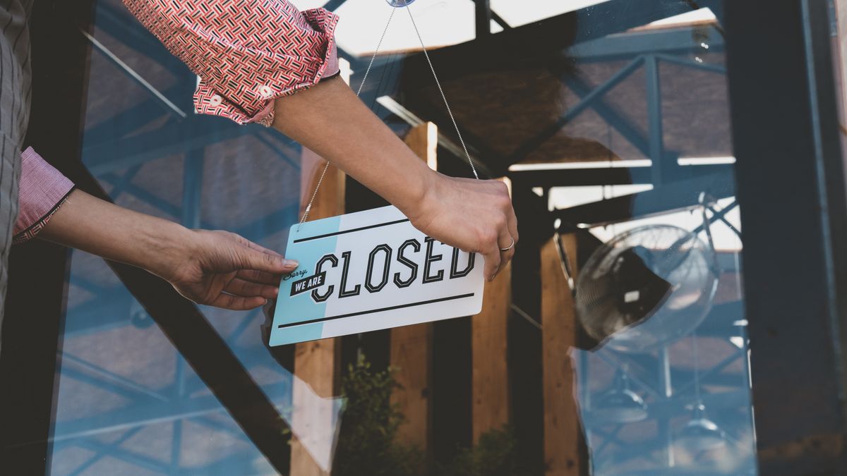 Restaurant staff hangs up a closed sign to show that the restaurant is closed for the day.