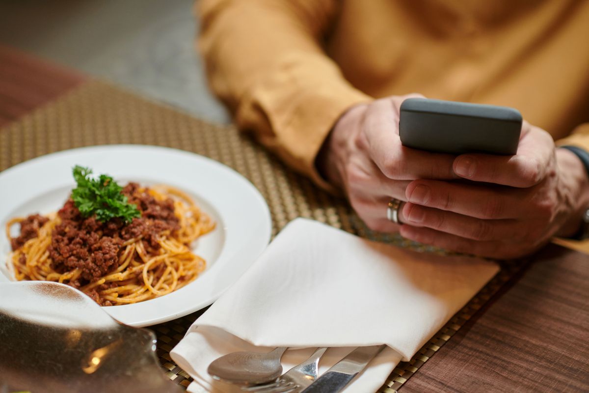 A restaurant guests checks their mobile phone