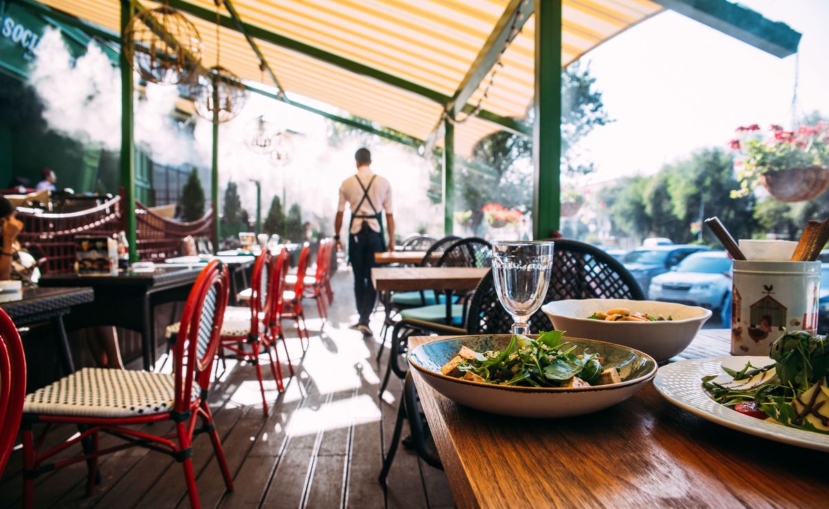 A restaurant server prepares a covered outdoor patio for summer