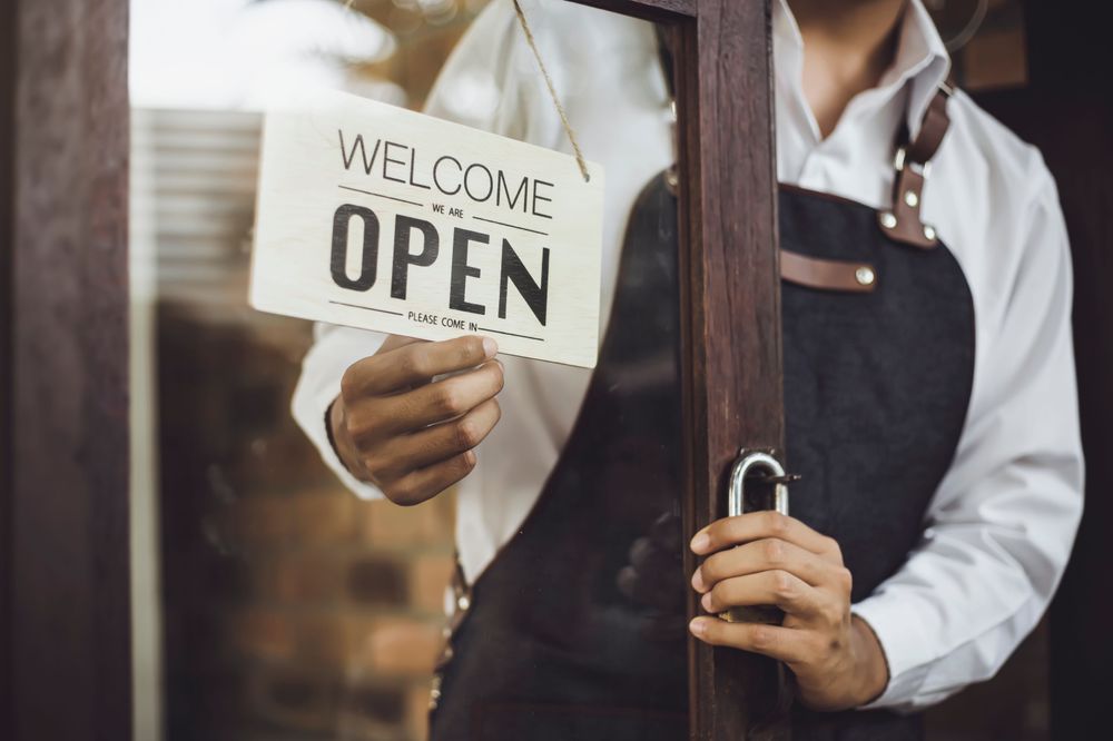 Restaurant worker flipping the entrance sign to "Open"