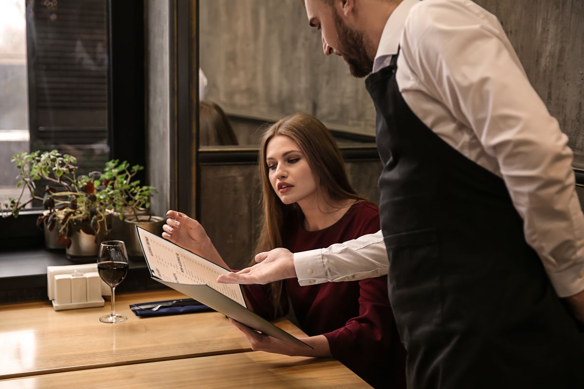 Restaurant guests ordering on a menuwith a restaurant staff.