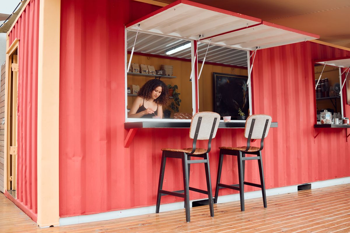 A server prepare an order from inside her pop-up restaurant