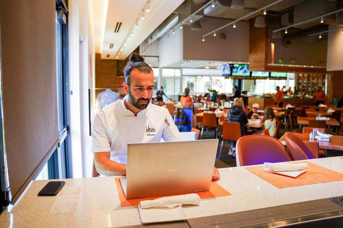 A restaurant manager looks at restaurant POS sales reports on a laptop