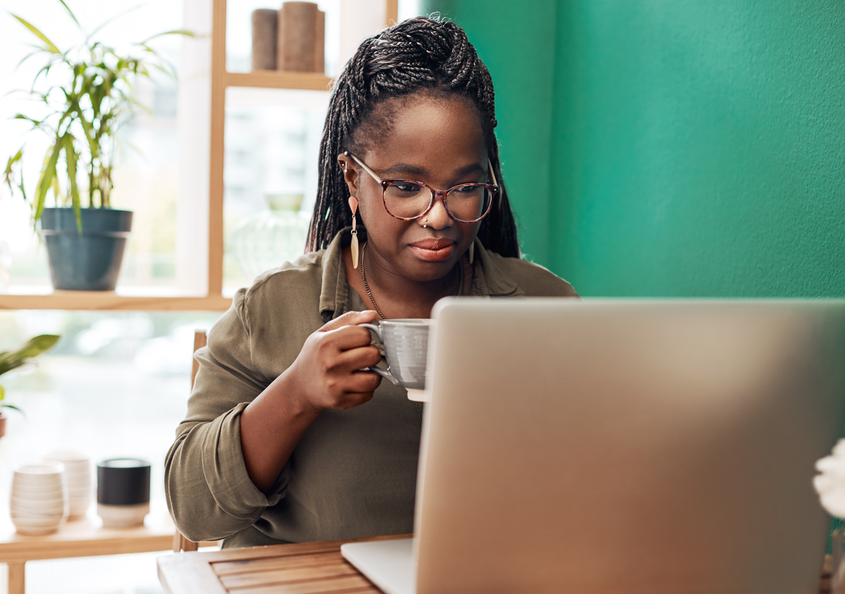 Woman applying for a job post while drinking coffee by her work laptop.