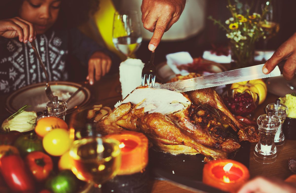 A family cuts into a Thanksgiving turkey