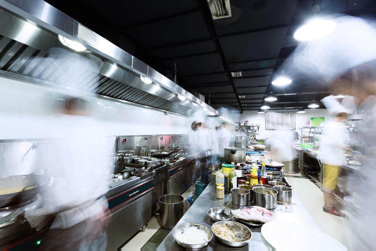 A restaurant kitchen with chefs working and moving quickly to cook meals for restaurant guests.