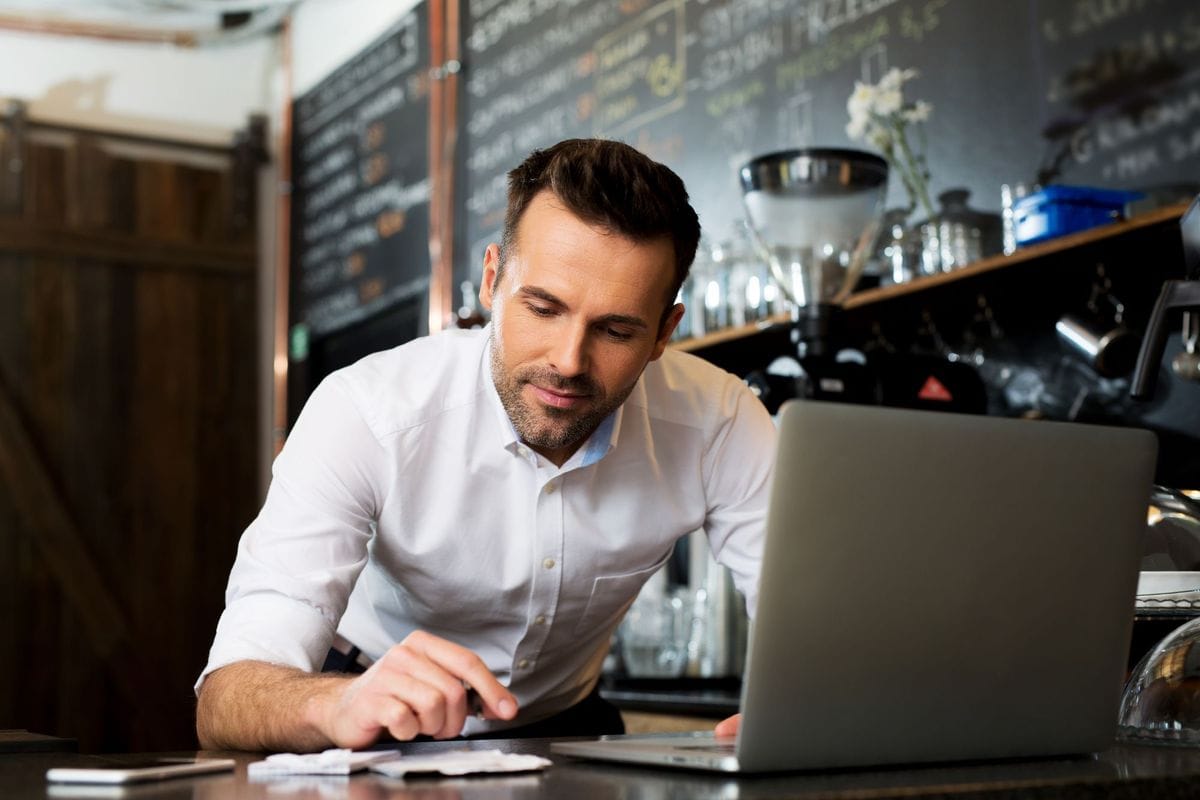 Restaurant owner on a laptop calculating his break-even point.