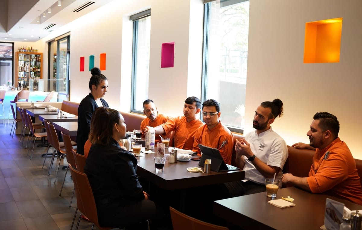 A restaurant manager meets with staff to discuss their restaurant schedule