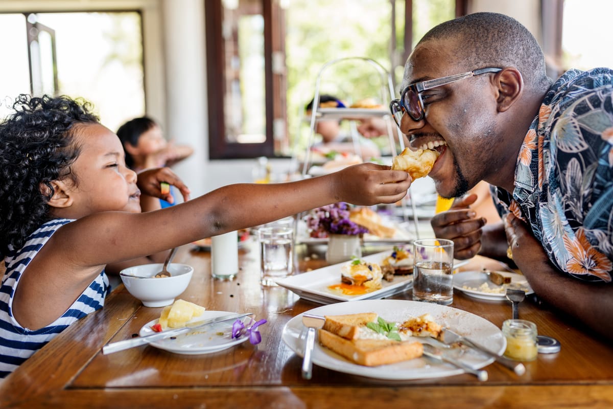 A parent and child enjoying food during restaurant week in the city.