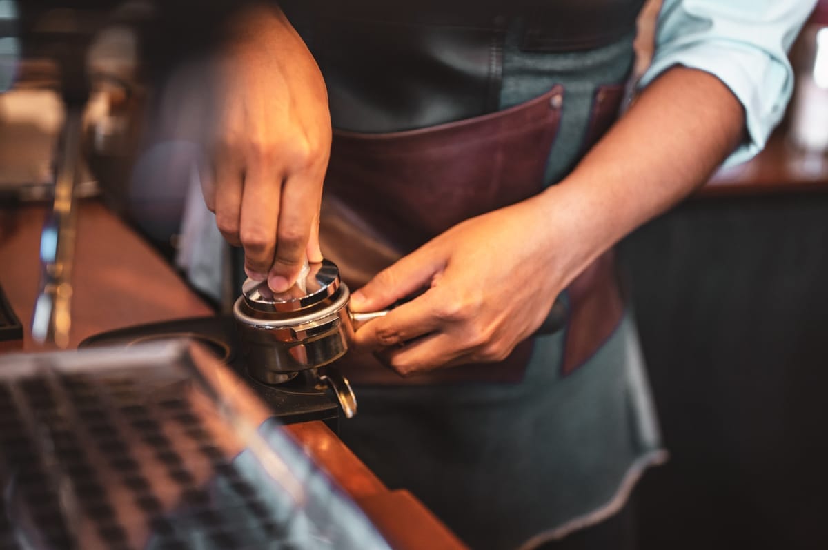 Barista making an americano with an espresso machine.