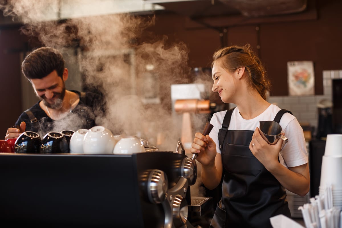 Baristas in a coffee shop brewing and smiling coffee for their guests.