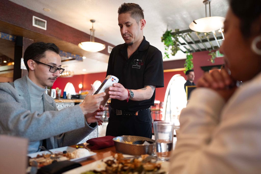 How much should you tip at a restaurant? A guest tips using handheld pos system. 