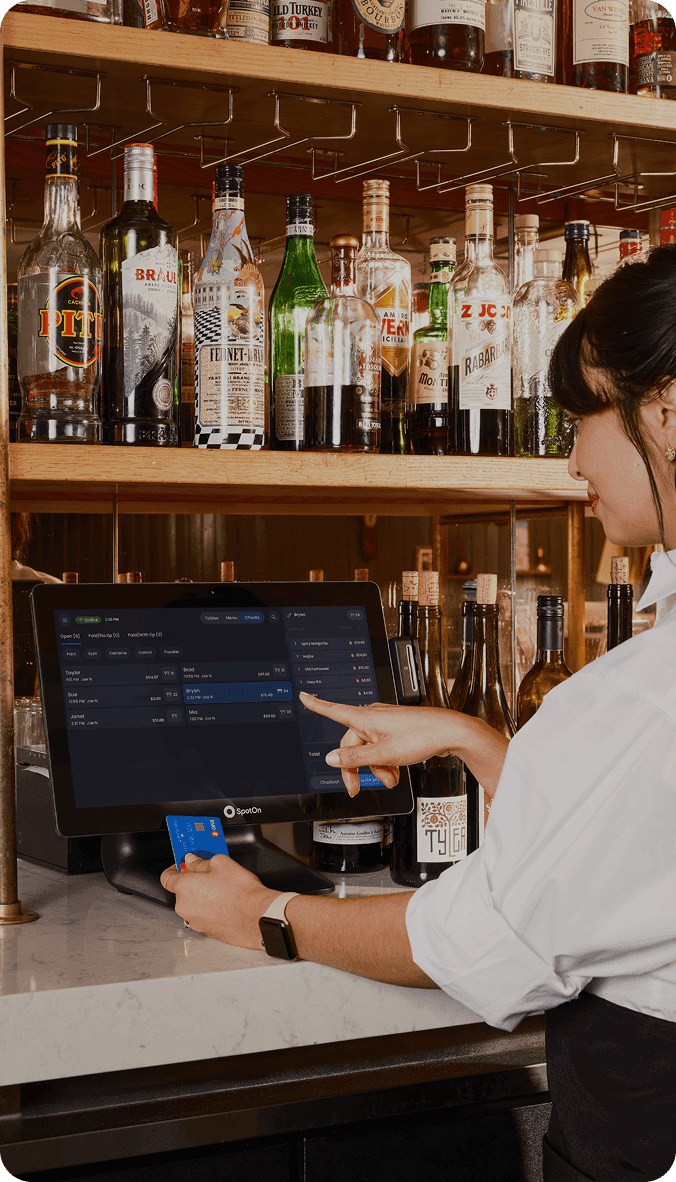 Bartender using SpotOn POS system while guest enjoys a cocktail
