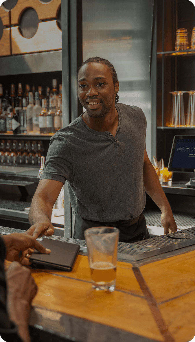 Bartender smiling and taking payment at SpotOn POS in a brewery