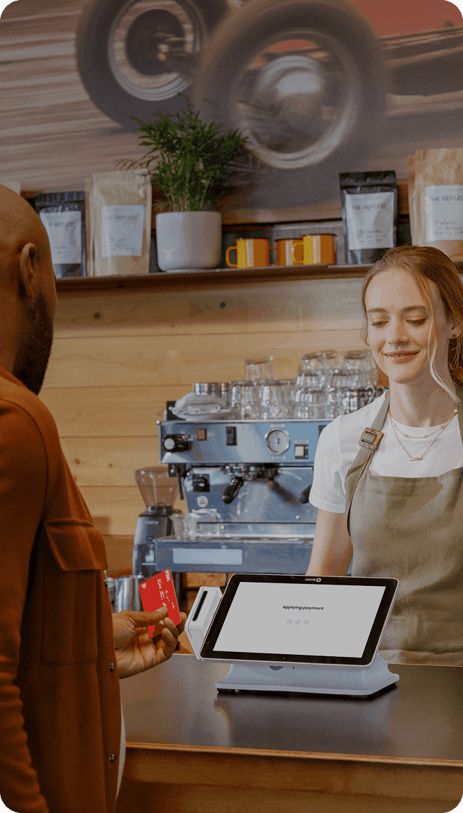 Barista smiling while taking card payment on SpotOn POS at a cafe