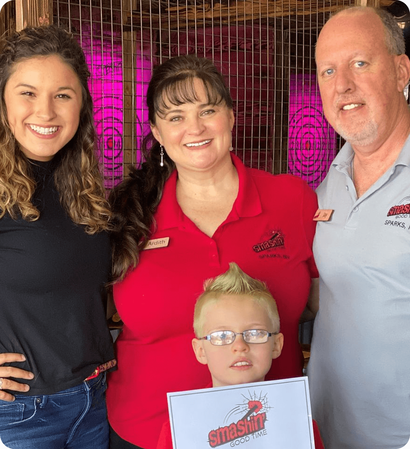 Group of four smiling people at a restaurant, including a child holding a flyer.
