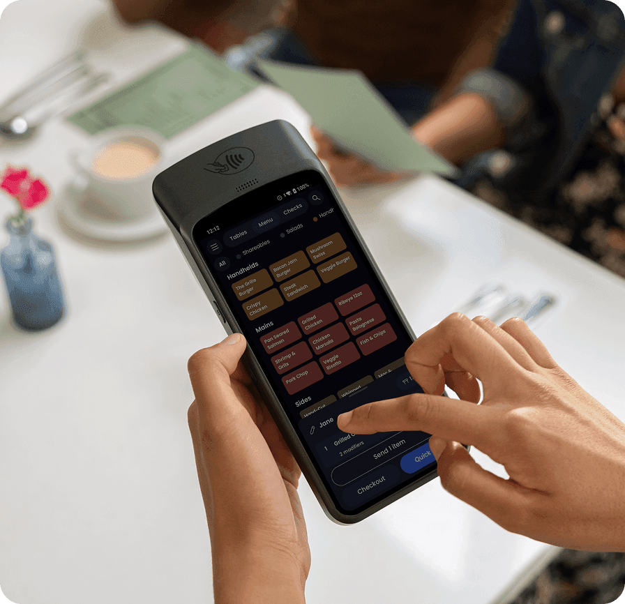 Server using SpotOn handheld POS device at restaurant table
