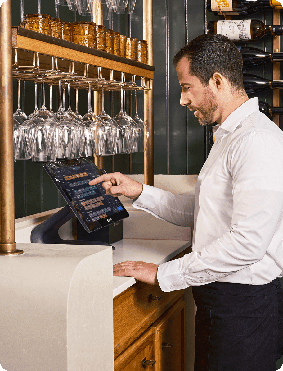 Bartender using SpotOn point-of-sale terminal behind bar