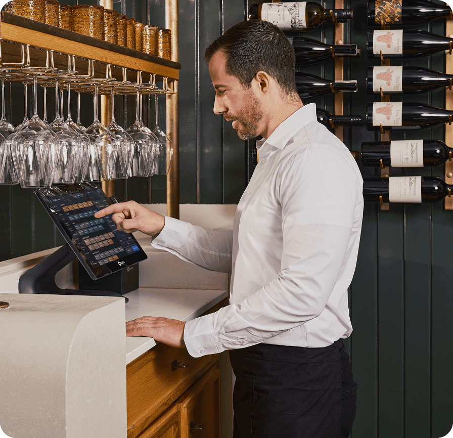 Bartender using SpotOn point-of-sale terminal behind bar