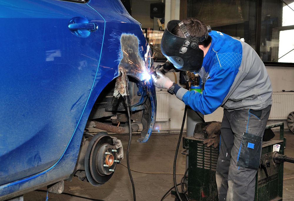 A man repairing a car in an auto shop.