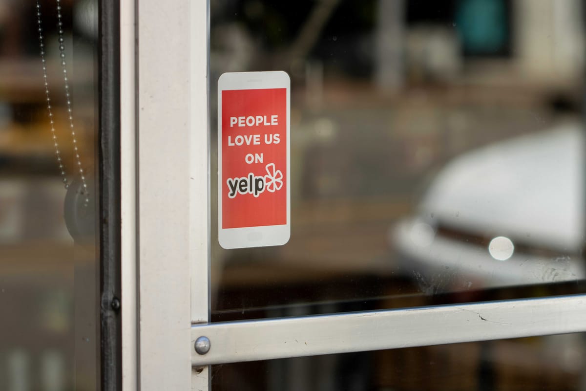 A sticker says "People love us on Yelp" on the front of a small business door