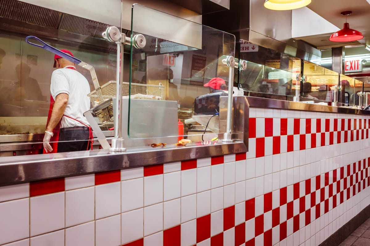 Staff cooking behind the counter at a fast food restaurant. Learn about the Illinois minimum wage laws.